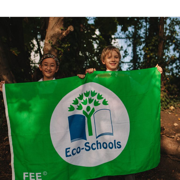 2 students holding up Eco Schools flag