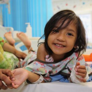 young girl learning forward on a hospital bed